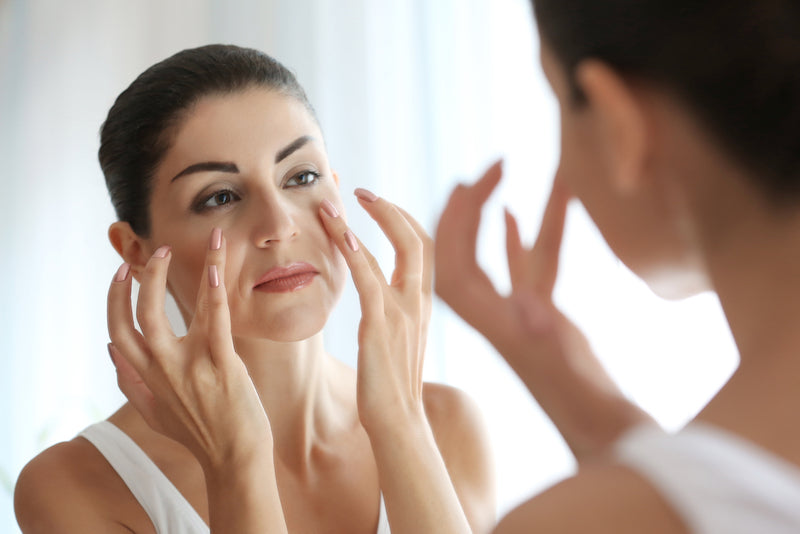 woman checking her skin elasticity in mirror